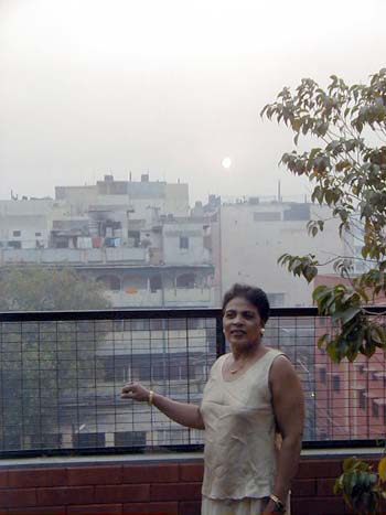 Rita on our balcony in Delhi with the sun rising behind her